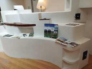 A white, curved reception desk with a lamp, brochures, and a small shelf.