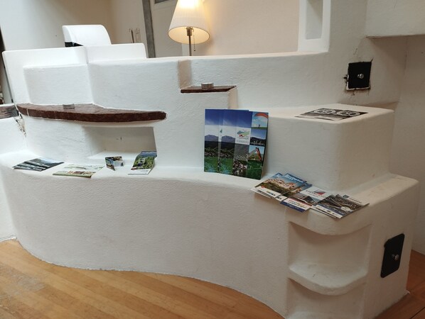 A white, curved reception desk with a lamp, brochures, and a small shelf.