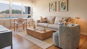 A modern living room with a sofa, armchair, coffee table, and a dining area with chairs and a table. - Playa de La Concha 6 by FeelFree Rentals (Donostia)
