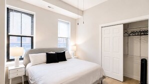 Ein Schlafzimmer mit einem Bett, Nachttischen, einer Lampe, einem Kleiderschrank und einer Heizung.