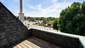 A balcony with a view of a parking lot and surrounding greenery. - 1BR Opposite SLU Hospital · Parking · Long Stays (St. Louis)