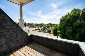 Un balcon donnant sur un parking et sur la végétation environnante.