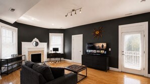 A living room with a fireplace, a television, and a sofa. - 1BR Opposite SLU Hospital · Parking · Long Stays (St. Louis)
