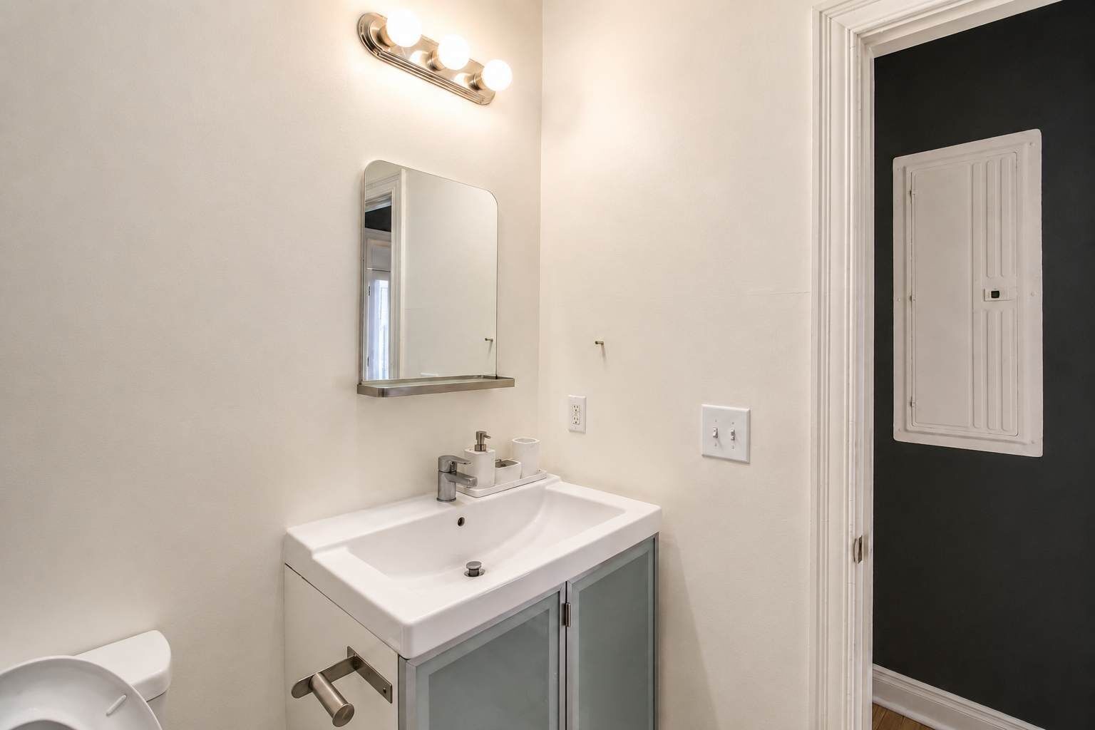 A bathroom with a white sink, a mirror, and a vanity cabinet.