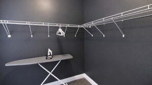 A laundry area with a wall-mounted drying rack, an ironing board, and a hanging clothes rack. - 1BR Opposite SLU Hospital · Parking · Long Stays (St. Louis)