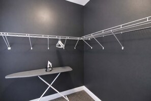 Un espace dédié à la lessive, équipé d’un étendoir mural, d’une planche à repasser et d’un portant à vêtements.