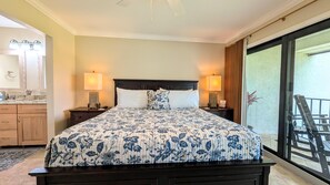 A bedroom with a large bed, two bedside tables with lamps, a nightstand, a bathroom with a mirror, and a balcony with a chair. - NEW to Rentals, Completely Upgraded, Desirable location 2nd floor Villa (Panama City Beach)