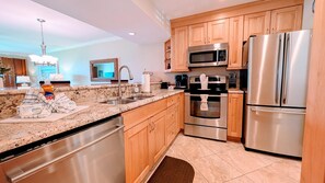 Eine moderne Küche mit Granit-Arbeitsplatten, Edelstahlgeräten, Holzschränken und einem eingebauten Backofen.