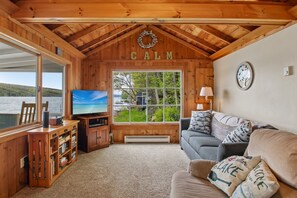 Ein Blick in die Holzhütte: Ein Fernseher, eine Couch und ein Seeblick.