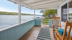 Un espace extérieur abrité avec vue sur un lac, une chaise en bois et une table bleue.
