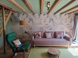 En stue med en grøn lænestol, en pink sofa og et træbord.