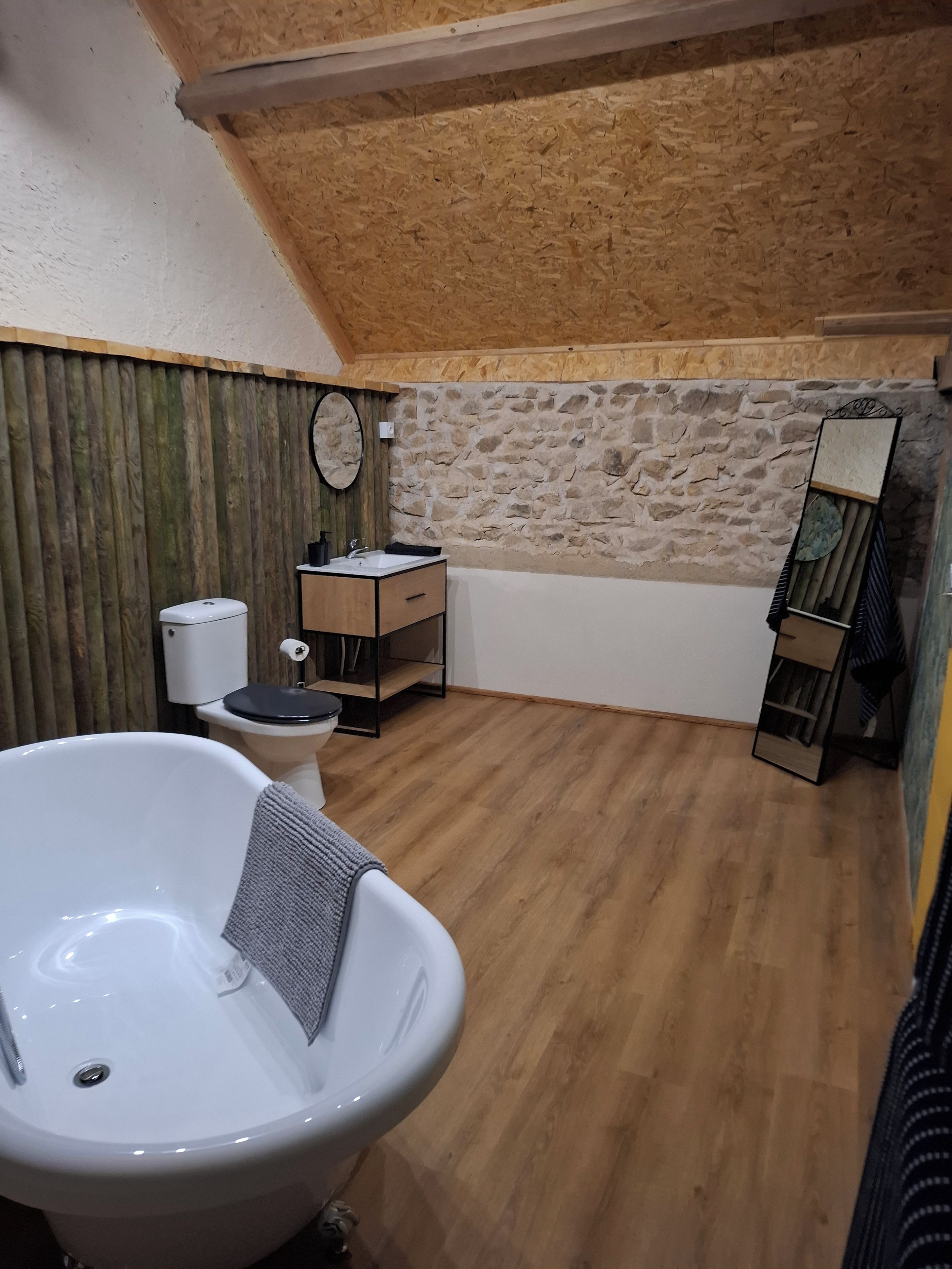 Et badeværelse med badekar, toilet og en lille vask med spejl.