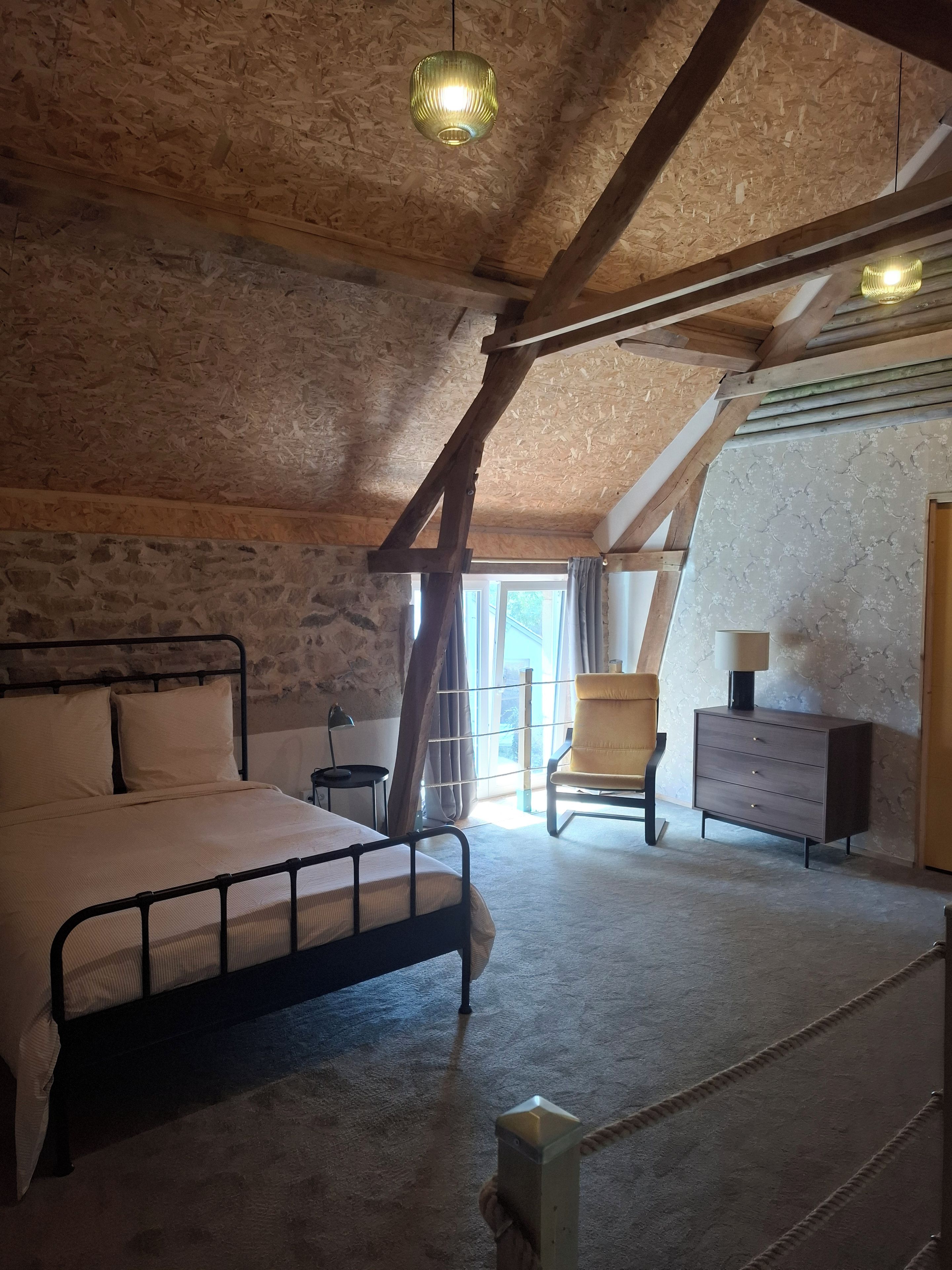 A bedroom with a bed, a chair, a dresser, and a window.