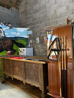 A bar area with a wooden bar counter, pool cues, and a mural on the wall. - Fabulous house in the charming countryside of Bussières w/hot tub. Pet-friendly! (Bussières)
