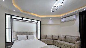 A modern bedroom with a large bed, a sofa, and a ceiling light fixture. - Sasha Collection at Stone Heights -AC, Pool & Secure (Hurghada)