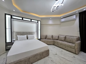Ein modernes Schlafzimmer mit einem großen Bett, einer Couch und einer Deckenleuchte.