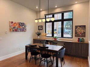 A dining area with a wooden table and chairs, a window with a view of the outside, and artwork on the walls. - Beautiful 4-bedroom home in scenic Ouray, ideal for families and groups (Ouray)