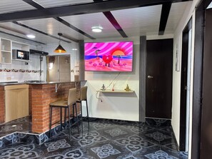 A modern kitchen with a brick accent wall, a bar area with stools, a flat-screen TV, and a patterned floor. - Apartment YKI Downtown Bogota (Bogotá)