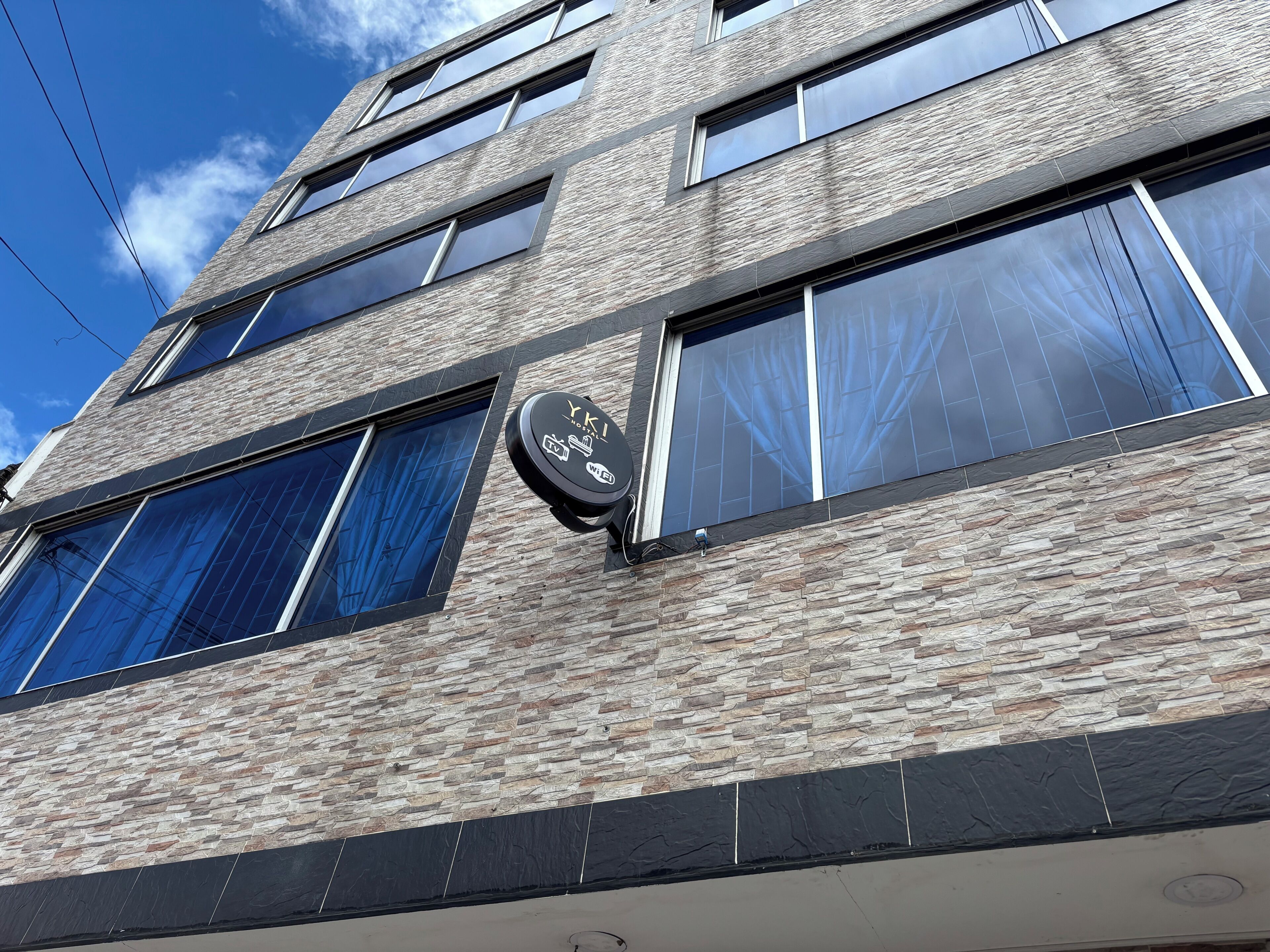A multi-story building with a stone facade, large windows, and a sign indicating a hotel.