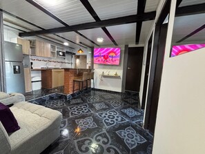 A modern kitchen with a bar area, a sofa, and a patterned floor. - Apartment YKI Downtown Bogota (Bogotá)