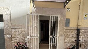 A building entrance with a metal gate, potted plants, and a number sign. - Mediterranean Deluxe Stone House (Molfetta)