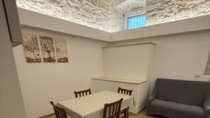 A dining area with a table and chairs, a sofa, and a stone-tiled floor. - Mediterranean Deluxe Stone House (Molfetta)