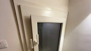 A closed door with a glass panel, a white wall, and a light switch. - Mediterranean Deluxe Stone House (Molfetta)