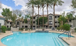 A swimming pool with lounge chairs, palm trees, and a building with balconies. - Scottsdale Retreat: Pool & Sauna (Scottsdale)