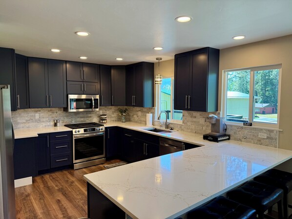 A modern kitchen with dark cabinets, a large island, and a view of the outdoors.