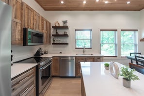 Una cocina moderna con armarios de madera, lavavajillas de acero inoxidable y una isla grande con un lavabo.
