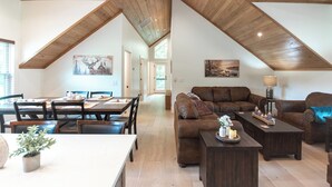 A spacious loft with high ceilings, a dining area, a living room with a sofa and coffee table, and artwork on the walls. - Luxury Barndominium w/ Hot Tub, Wifi & Trout Fishing (Franklin)