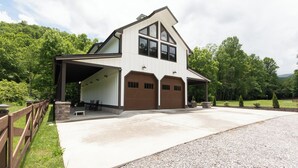 A two-story house with a covered porch, a garage, and a driveway. - Luxury Barndominium w/ Hot Tub, Wifi & Trout Fishing (Franklin)