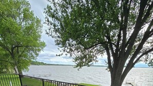 A wooden deck with a table and chairs, overlooking a body of water.
