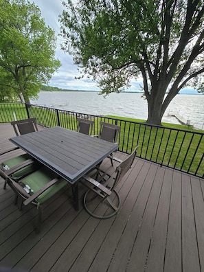 A wooden deck with a table and chairs, overlooking a body of water.