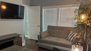 Un salon moderne avec un canapé, un ordinateur portable, une télévision et une plante.