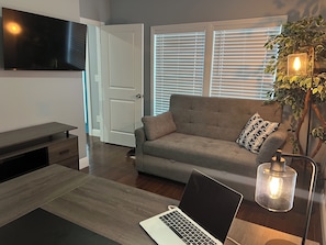 A modern living room with a sofa, a laptop, a TV, and a plant. - 3-bedroom house in charming Atlanta with cool AC comfort (Atlanta)