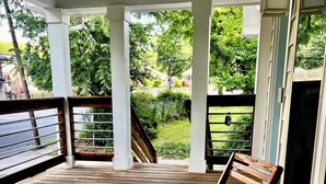 Une terrasse en bois avec deux chaises en bois et une rambarde blanche.