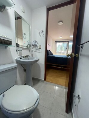 A bathroom with a toilet, sink, and mirror. There is a door leading to a bedroom with a bed and a window. - APARTMENT IN CDMX, CLOSE TO WTC (Ciudad de México)