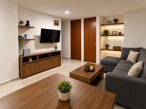 A modern living room with a flat-screen TV, wooden furniture, a grey sofa, and a coffee table with a plant. - APARTMENT IN CDMX, CLOSE TO WTC (Ciudad de México)