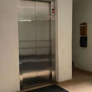 An elevator with a metallic finish, a red emergency stop button, and a small trash bin on the wall. - APARTMENT IN CDMX, CLOSE TO WTC (Ciudad de México)