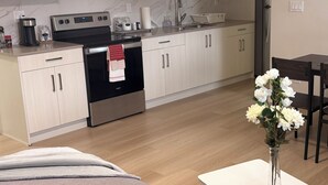 Une cuisine moderne dotée d’appareils électroménagers en acier inoxydable, de meubles blancs et d’un coin repas avec une table et des chaises blanches.