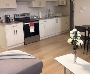 A modern kitchen with stainless steel appliances, white cabinetry, and a dining area with a white table and chairs.