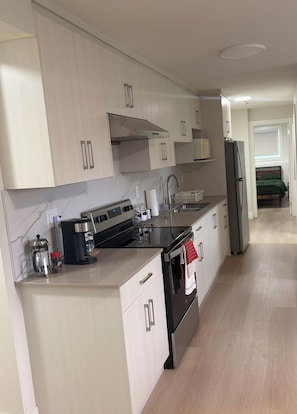 A modern kitchen with a stove, sink, and refrigerator.