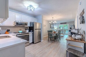 A modern kitchen with stainless steel appliances, a dining area with wooden furniture, and a view of the outdoors. - Beachfront Resort Villa Pool, Steps to the Sand (Hilton Head Island)
