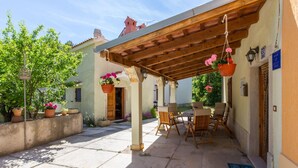 A covered outdoor seating area with wooden furniture and hanging flower baskets.