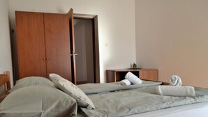 Quarto com cama, almofadas, guarda-roupa de madeira e mesa de cabeceira pequena.