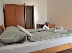 Ein Schlafzimmer mit einem Bett, Kissen, einem Holzschrank und einem kleinen Nachttisch.