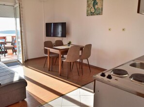 Ein Essbereich mit Tisch und Stühlen, einem Fernseher an der Wand und einer Küche mit Herd.