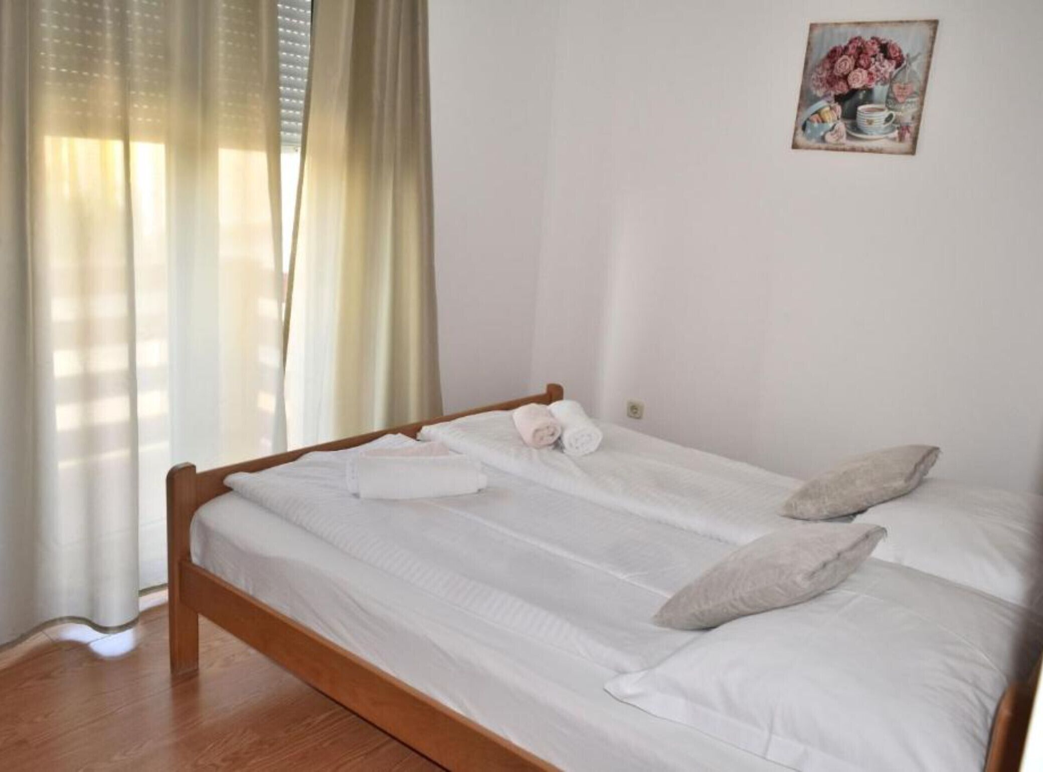 Un lit simple avec du linge de lit blanc, une tête de lit en bois et deux oreillers.