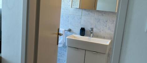 A bathroom with a white sink, a mirror, and a towel rack.